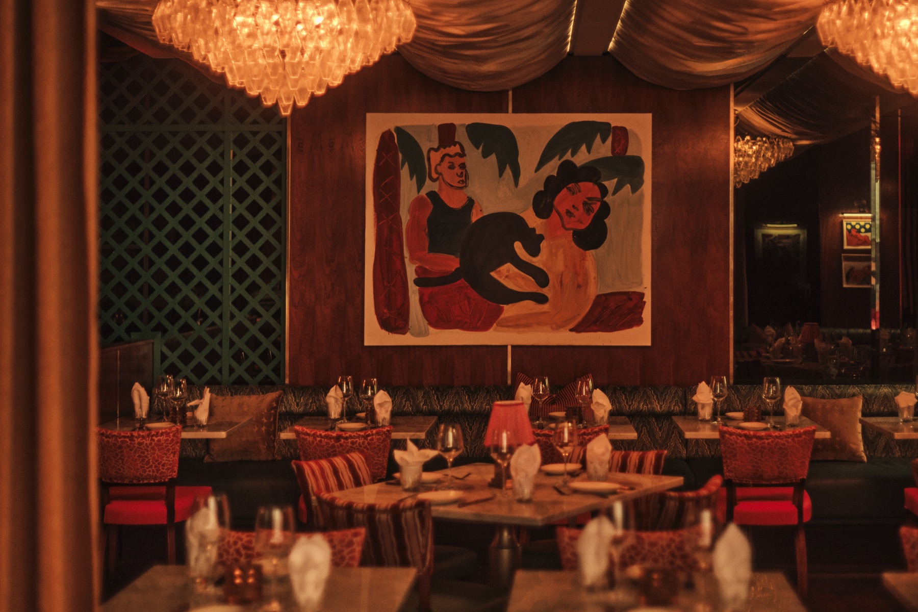 Art wall, chandeliers and velvet banquettes in the Sirrah dining room